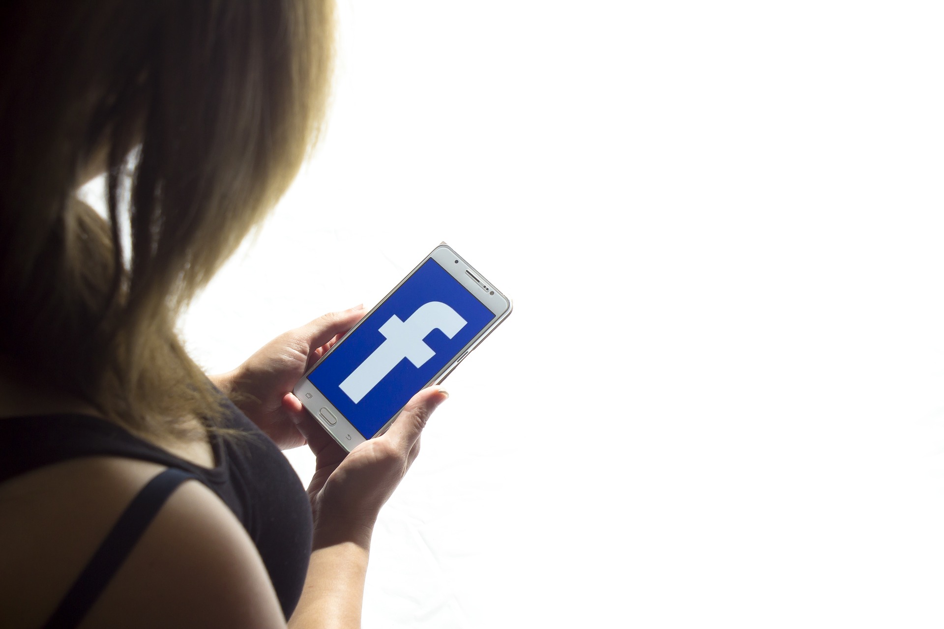 kollar på mobilskärmen med facebook ikon